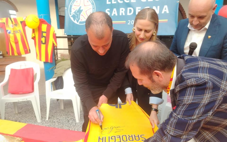 Un momento di incontro del Lecce Club Sardegna: una maglia giallorossa viene autografata davanti allo striscione del club.